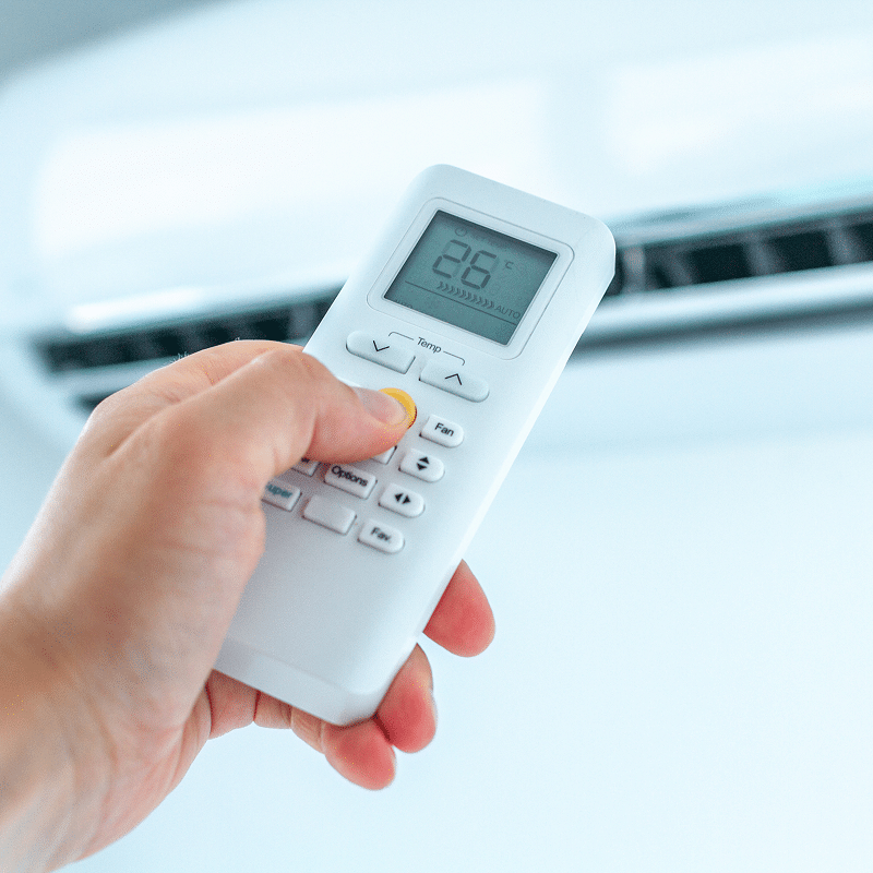 Main ajustant une télécommande blanche de climatisation. L'écran affiche la température '86°C', le mode 'AUTO', et des ondes. Boutons Temp, Fan, Options, Fav visibles.