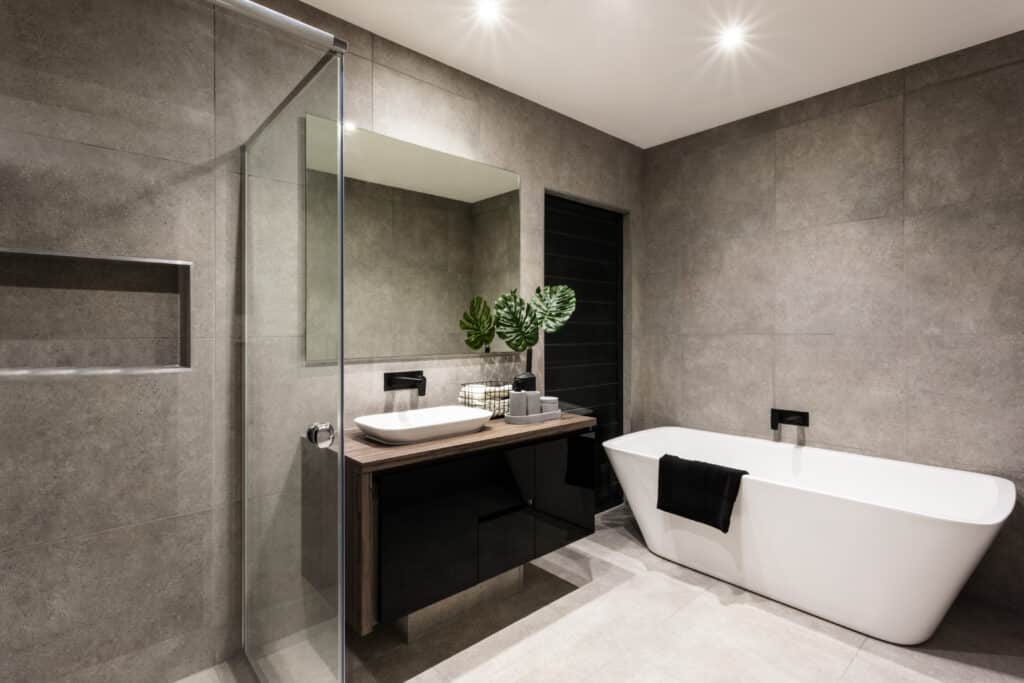 Salle de bain moderne grise avec douche séparée, lavabo vasque sur meuble bois foncé et baignoire îlot blanche.